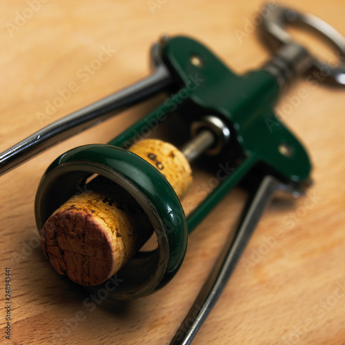 GREEN LEVER CORKSCREW AND WINE CORK ON WOODEN TABLE photo