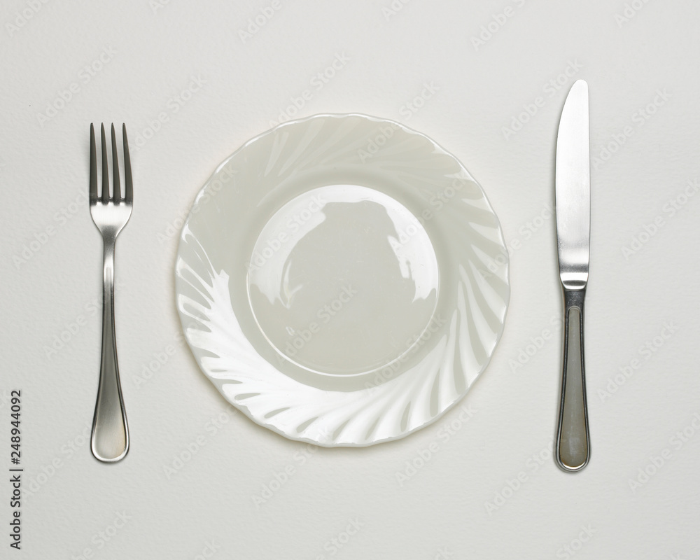WHITE PLATE WITH KNIFE AND FORK ON WHITE BACKGROUND