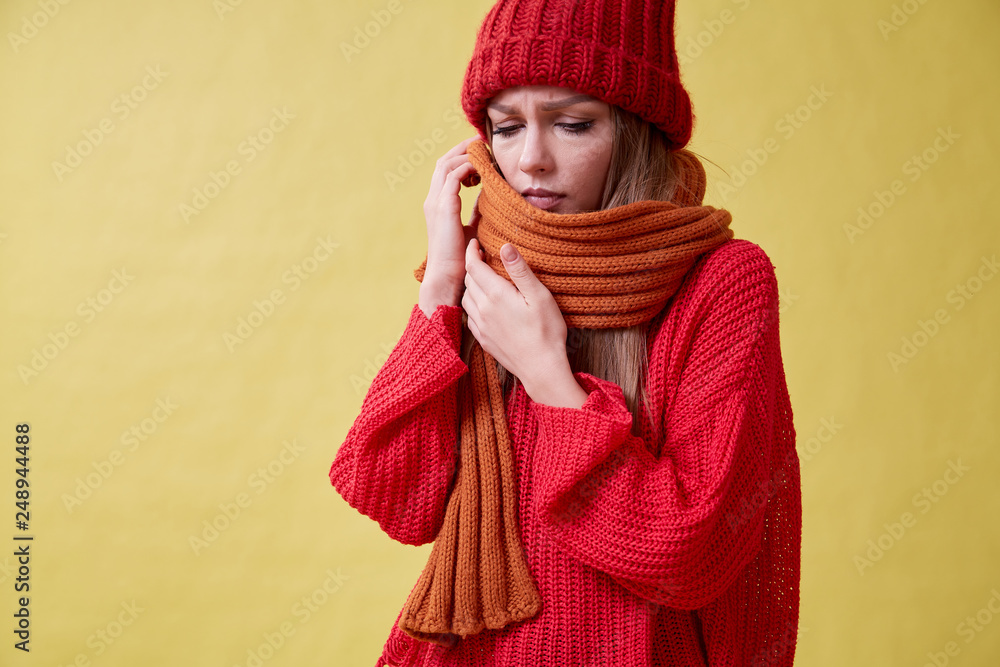 Ill girl in the red sweater standing on the yellow background, sore throat Ill girl in the red sweater standing on the yellow background, sore throat