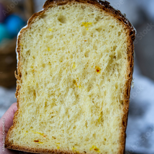 Half-cut homemade sweet easter bread in the hands of a baker's woman. Slice of easter orthodox sweet bread, kulich. Beautiful lace crumbs rolls. Close up, selective focus, copy space.
