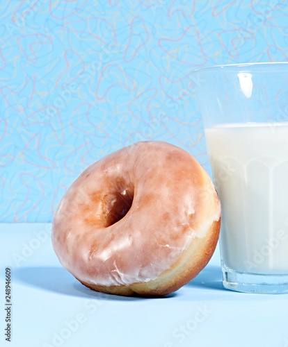 Glazed donut leaning against glass of milk photo