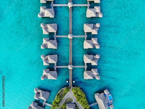 Aerial view of overwater bungalow villas with thatched roofs in the Bora Bora lagoon in French Polynesia