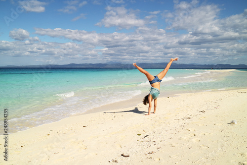 young woman doing a handstand on the beach