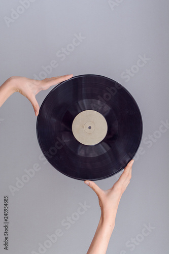 Hand holding vinyl record isolated on bright background, retro style