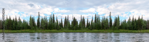 Panorama of the coastline, overgrown with wild forest. The view from the river. Travel to the Polar Urals in Russia.