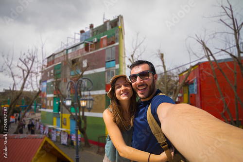 Happy tourist couple taking selfie in the Caminito, the colorful street museum in La Boca barrio, Buenos Aires, Argentina, South America