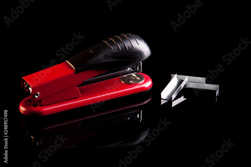 red stapler with staples on a black background