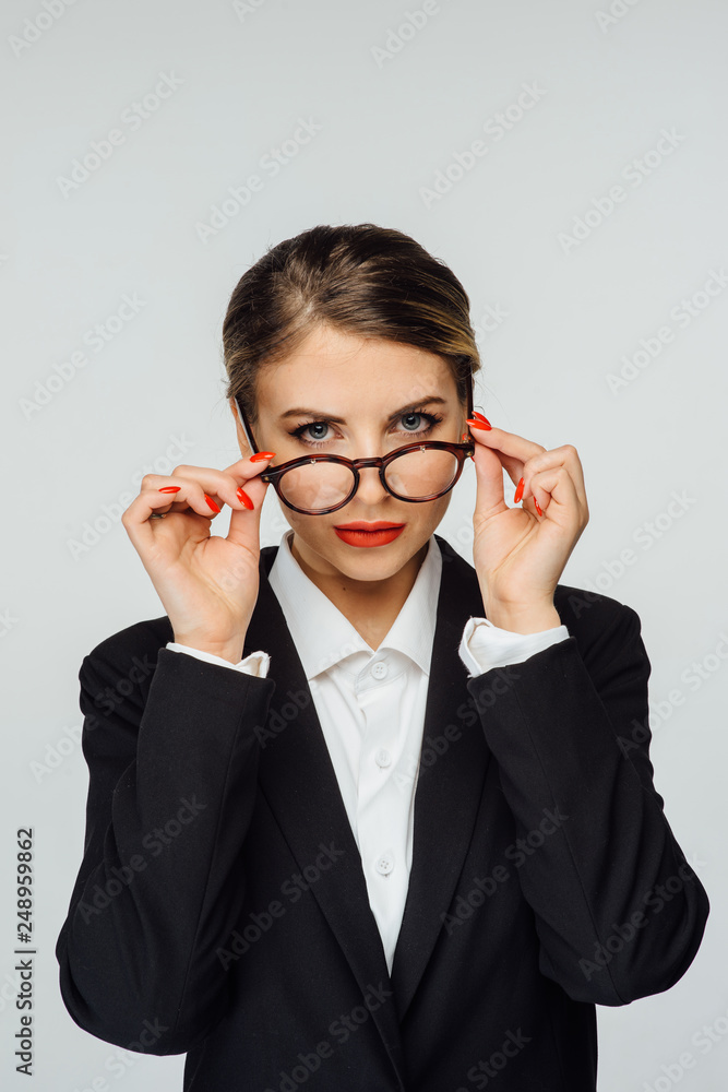 sexy business woman in glasses and in modern suit is standing on a white background
