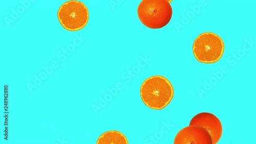 Whole oranges and slices against cyan background. Oranges rotating and falling down. Abstract background photo