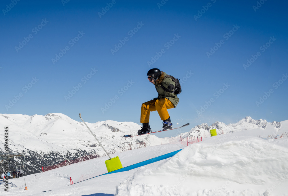 Jumping snowboarder with a blue and sunny sky in Zermatt, the swiss Alps