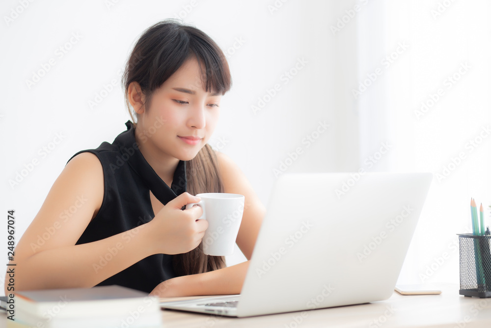 Beautiful young freelance asian woman smiling working and on laptop computer at desk office with professional, girl using notebook and drink coffee, business and lifestyle concept. Beautiful young freelance asian woman smiling working and on laptop computer at desk office with professional, girl using notebook and drink coffee, business and lifestyle concept.