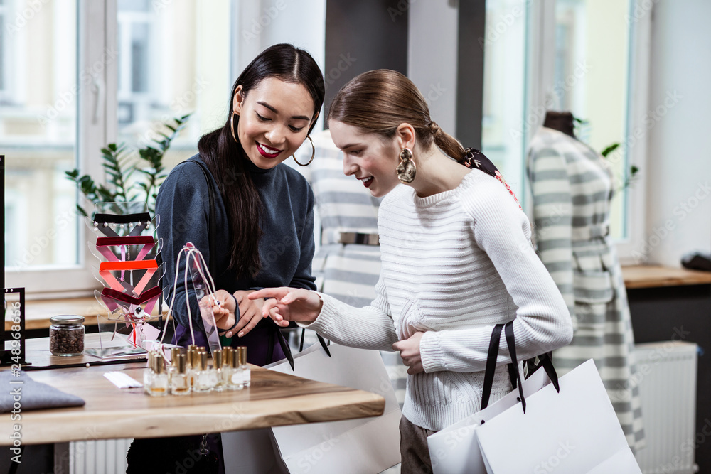 Brunette beautiful asian woman in a navy polo neck and her friend discussing adornments