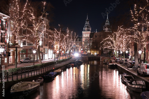 AMSTERDAM, NETHERLANDS - DECEMBER 12, 2018: illuminated trees and buildings reflected in water at Spiegelgracht Amsterdam in december by night