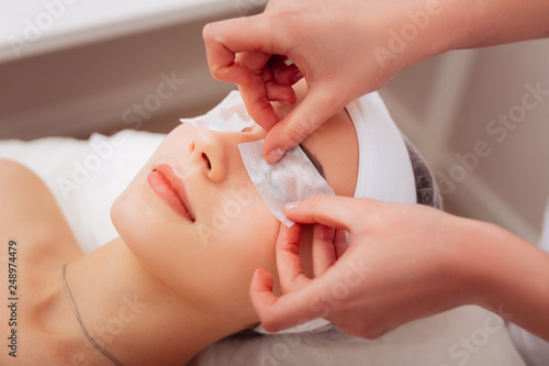 Nice professional female cosmetologist applying eye patches