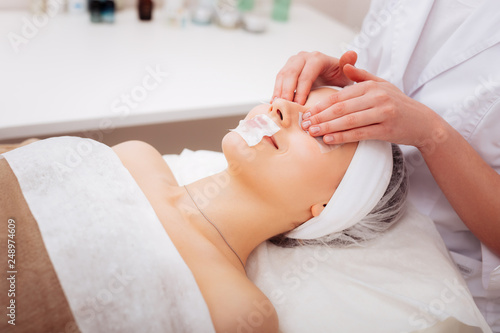 Nice professional beautician applying eye mask on the face
