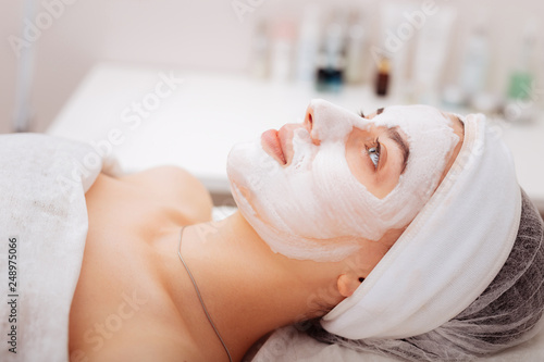 Pleasant young woman lying with a facial mask