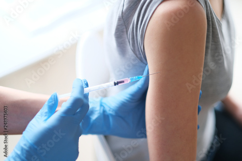 Young female doctor giving an injection to the patient.