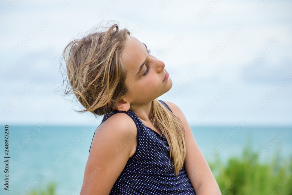 Criança modelo sentada em frente ao mar azul Criança modelo sentada em frente ao mar azul