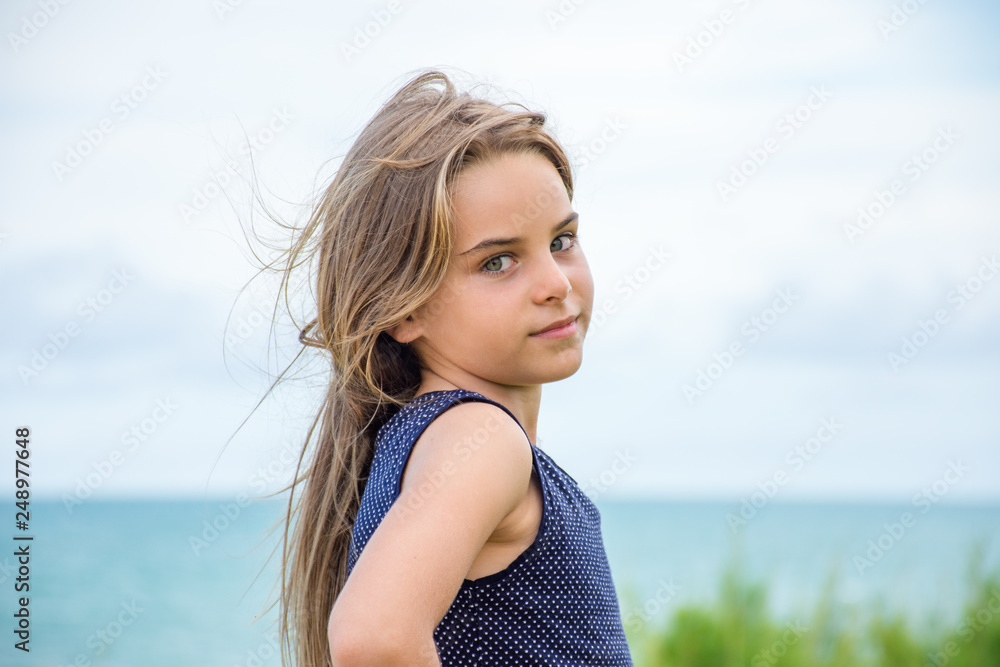 Criança modelo sentada em frente ao mar azul Criança modelo sentada em frente ao mar azul