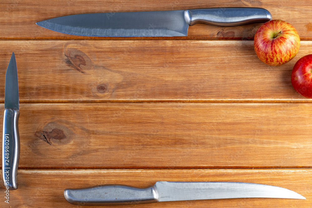 Rustic table of wooden strips with silver knives and a red apple. Ripe and sweet fruit for dessert Rustic table of wooden strips with silver knives and a red apple. Ripe and sweet fruit for dessert