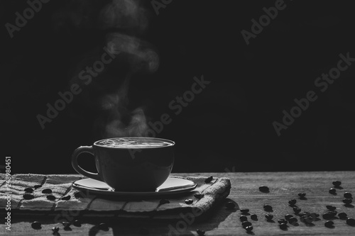 Hot coffee cup with organic coffee beans on the wooden table and blurred background with copy space