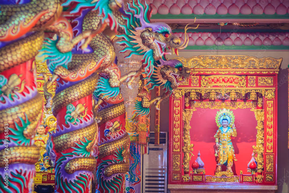 Obraz premium Colorful dragons and statue of Nezha, the protective deity in Chinese folk religion at Chinese public temple.