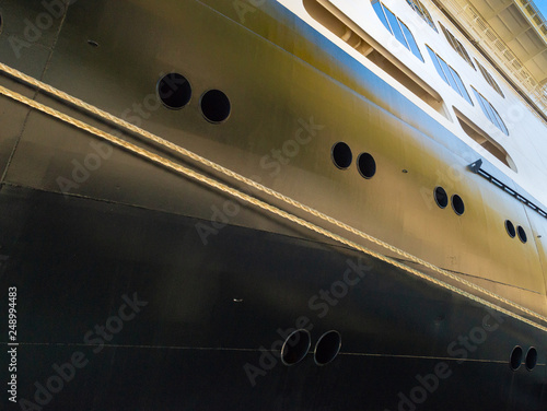 Rope mooring lines, portholes and windows near bow of berthed cruise ship.