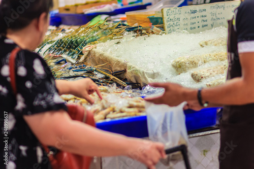 Unidentified woman at the seafood market is buying the extra large size of giant malaysian prawn (Macrobrachium rosenbergii) also known as the giant river prawn or giant freshwater prawn.