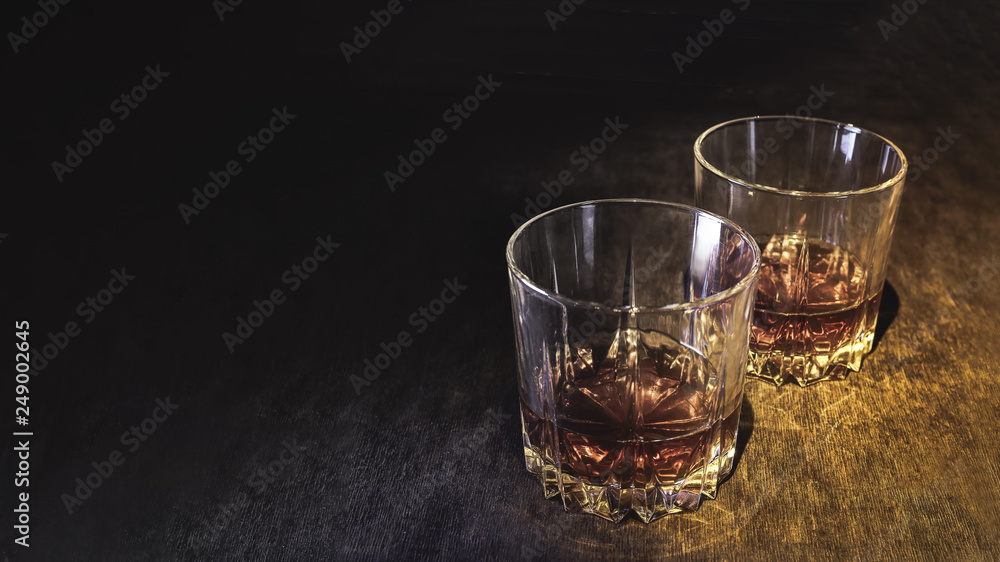 Whiskey in a glass on a dark wooden background. Whiskey in a glass on a dark wooden background.