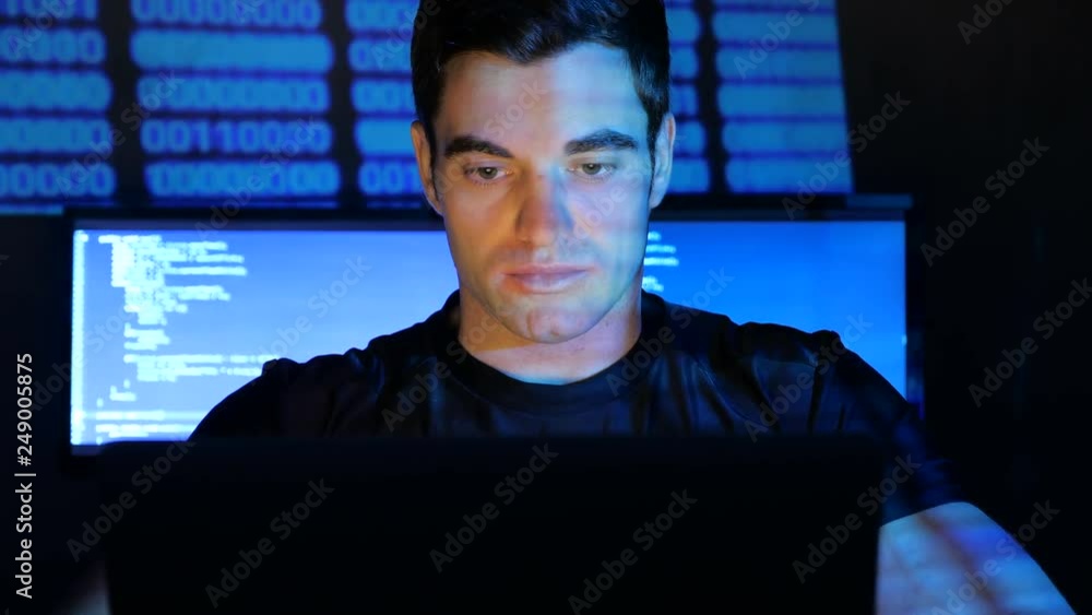 close up portrait of developer programmer looks at camera in a data center filled with monitor screens. Monitor screen is reflected on his face close up portrait of developer programmer looks at camera in a data center filled with monitor screens. Monitor screen is reflected on his face