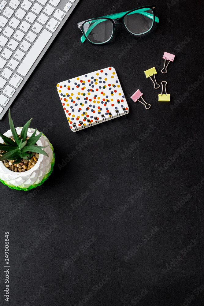 Obraz premium Work desk of creative person. Computer keyboard, glasses, bright stationery, plant on black background top view copy space