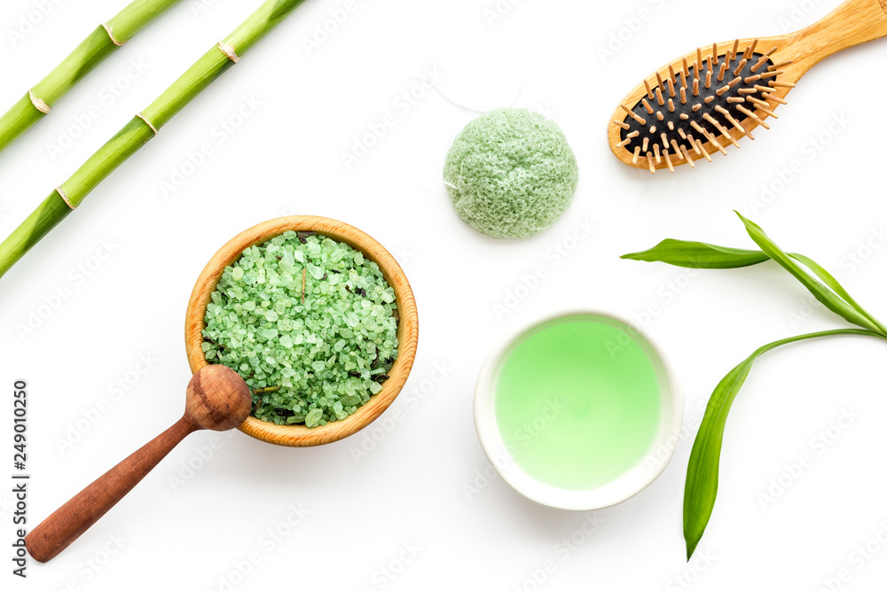 Asian spa treatment concept with natural ingredients. Spa salt, lotion, sponge near bamboo on white background top view pattern Asian spa treatment concept with natural ingredients. Spa salt, lotion, sponge near bamboo on white background top view pattern