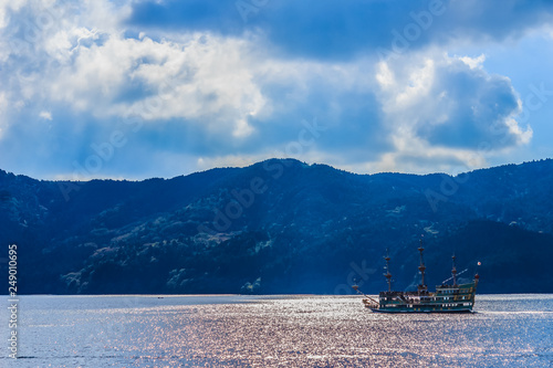 Tourist cruise ship on lake Ashi with mountains and blue sky on the background