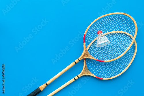 Badminton concept. Badminton rackets and shuttlecock on blue background top view copy space