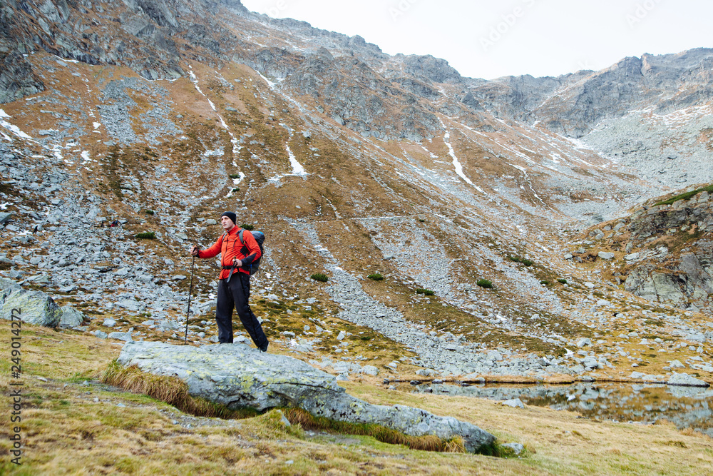 Fototapeta premium The young man of sporting physique rises to the mountain with sporting equipment