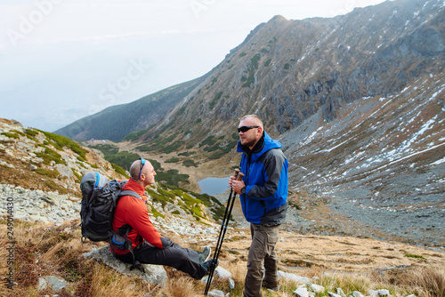 Two young sports men are sitting on top of the mountain with sporting gear