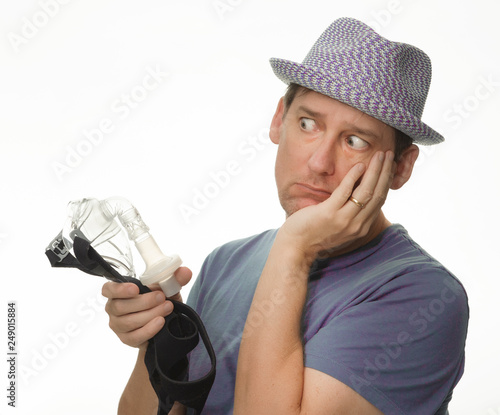 Frightened man holding a Cpap mask with a hat on photo