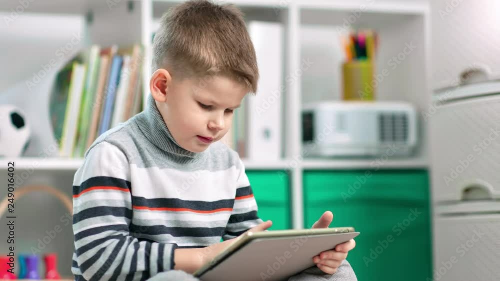 A child boy is using his tablet to surf the internet A child boy is using his tablet to surf the internet