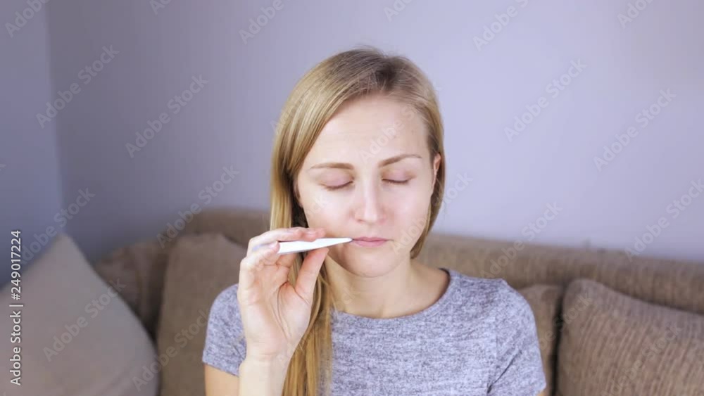 Portrait of a girl who measures temperature and wipes her nose with a tissue Portrait of a girl who measures temperature and wipes her nose with a tissue