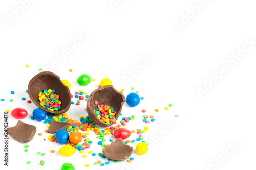 Broken Chocolate Easter Egg and multicolored sweets on a white background. Easter celebration concept