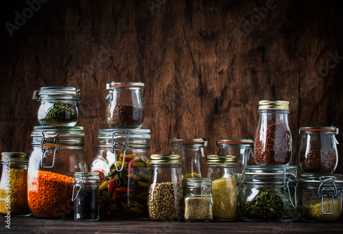 Stocks or set of cereals, pasta, groats, organic legumes and useful seeds in glass jars. Vegan source of protein and energy resources. Healthy vegetarian food. Domestic life scene. 