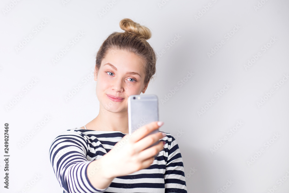 Close-up portrait of beautiful attractive blonde woman taking selfie on smartphone on white background Close-up portrait of beautiful attractive blonde woman taking selfie on smartphone on white background