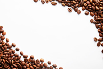 Roasted brown coffee beans scattered on white table with a lot copy space for text. Flat lay composition. Close up, top view, background.