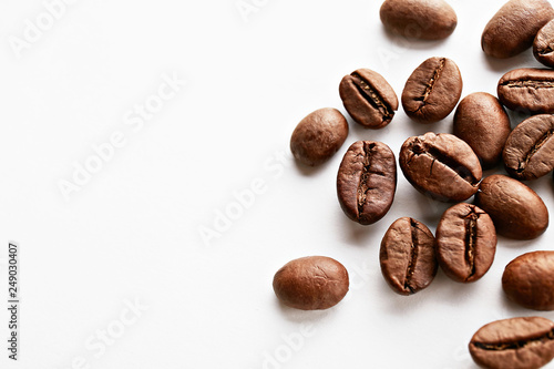 Roasted brown coffee beans scattered on white table with a lot copy space for text. Flat lay composition. Close up  top view  background.