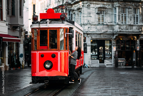 Girl in a vintage tram on the Taksim Istiklal street in Istanbul. Girl on public transport. Old Turkish tram on Istiklal street, Turkey. Portrait of a smiling young woman posing on a city street photo