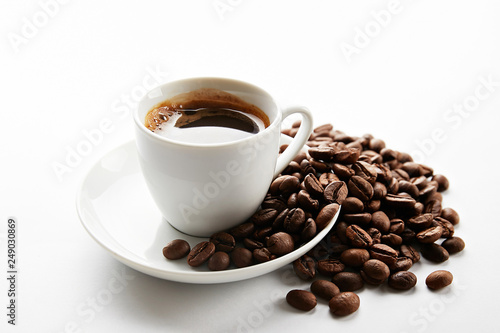 Coffee cup with roasted brown beans scattered on white table with a lot copy space for text. Flat lay composition. Close up, top view, background.