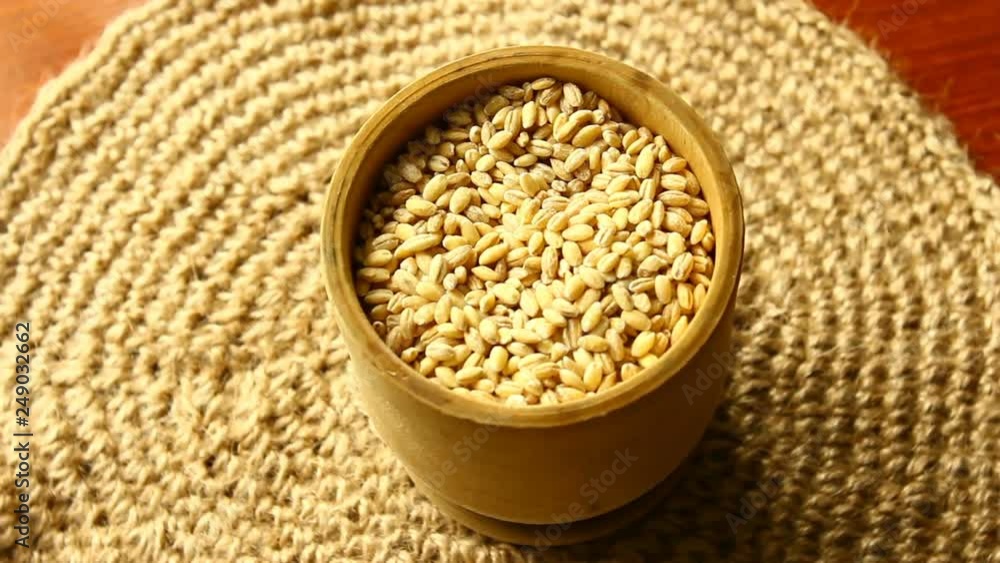Pearl barley in a wooden cup on gunny. Slow rotation. Pearl barley in a wooden cup on gunny. Slow rotation.
