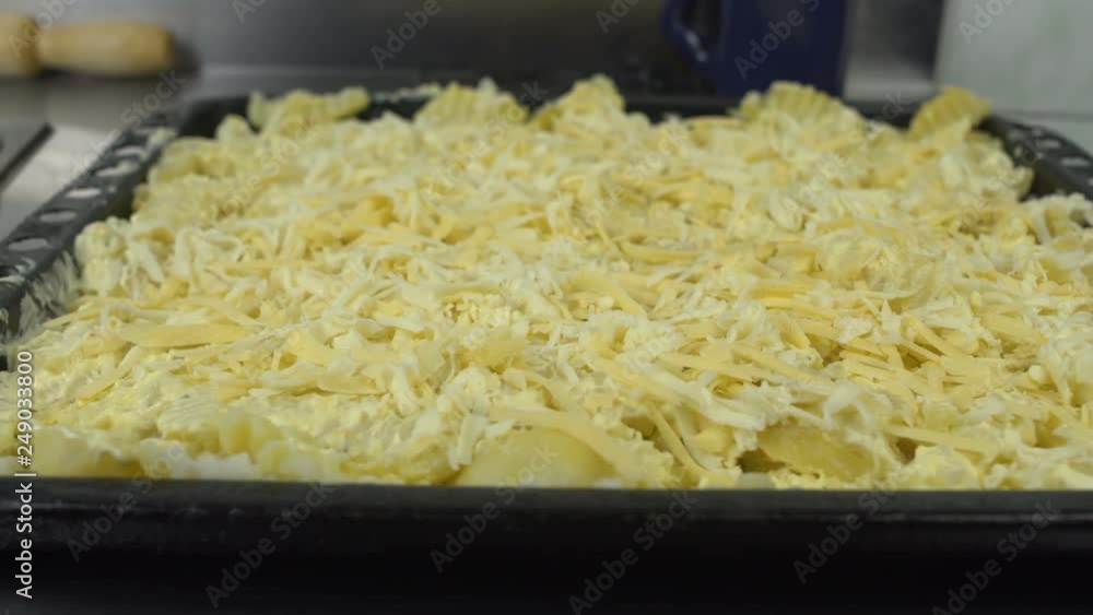 pieces of sliced potatoes with cheese are in the sheet pan or baking tray in the kitchen restaurant pieces of sliced potatoes with cheese are in the sheet pan or baking tray in the kitchen restaurant