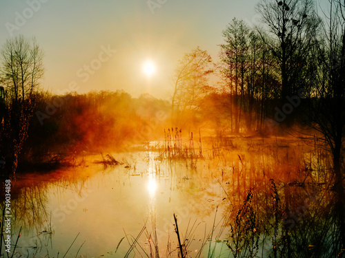 The river in the morning. Orange dawn over the meadow spill.