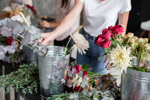 Close-up flowers in a metal bucket. Florist workplace. Woman arranging a bouquet with roses, chrysanthemum, carnation and other flowers. A teacher of floristry in master classes or courses